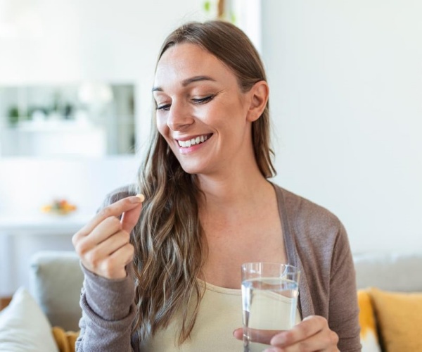 pregnant woman smiling while taking a supplement