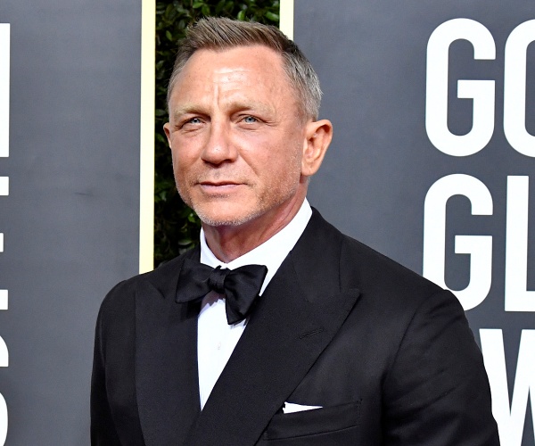 daniel craig stands on red carpet