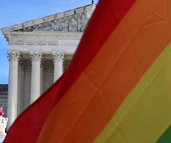 a gay pride flag flying in front of the united states supreme court building