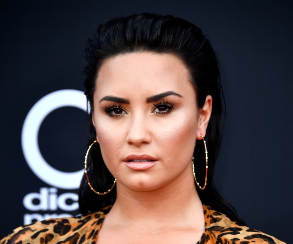 lovato in a leopard print top and hoop earrings