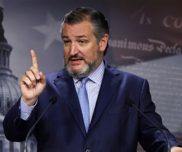 ted cruz stands at a podium and raises his finger while he speaks