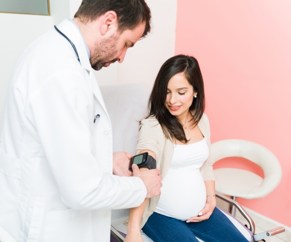 doctor taking blood pressure of pregnant woman