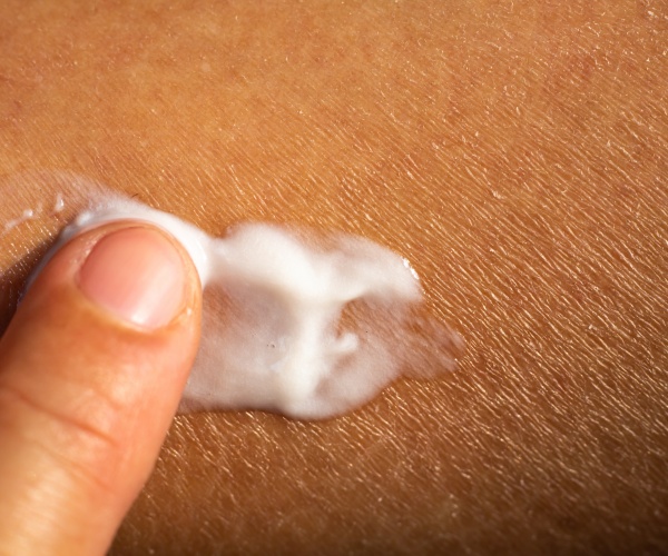 close up of dry skin, person putting lotion on it