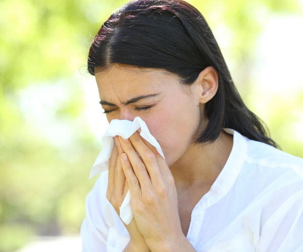 woman outside sneezing