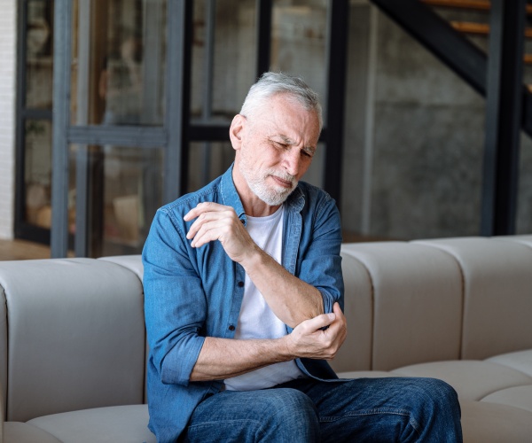 older man sitting on couch with elbow pain