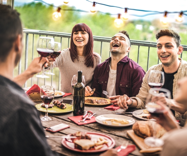 friends having fun drinking red wine at a balcony penthouse dinner party