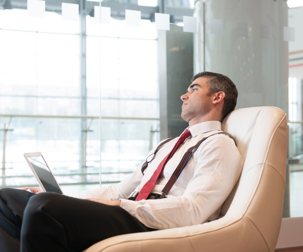 man at work with laptop on lap daydreaming out window