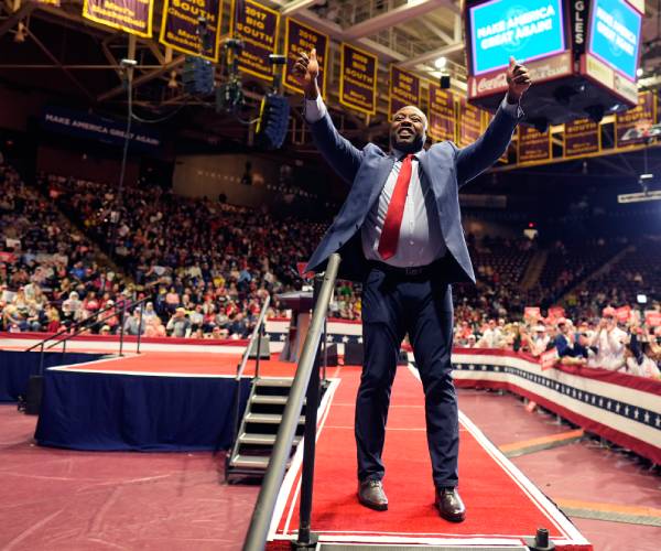 tim scott raises his hands at a rally