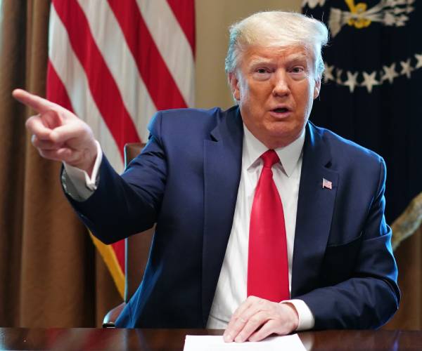 donald trump seated and pointing with one hand