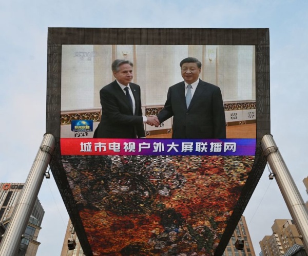 news broadcast shows footage of antony blinken meeting with xi jinping on a giant screen 