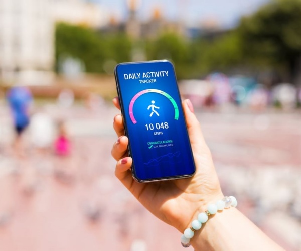 woman holding smartphone with step counter on screen