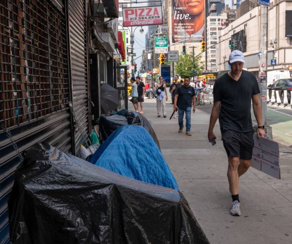 people walk by tents set up on the sidewalk in new york