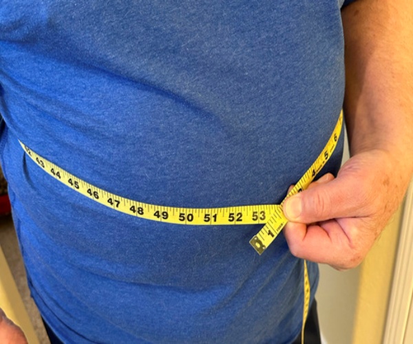 man using measuring tape to measure his waist