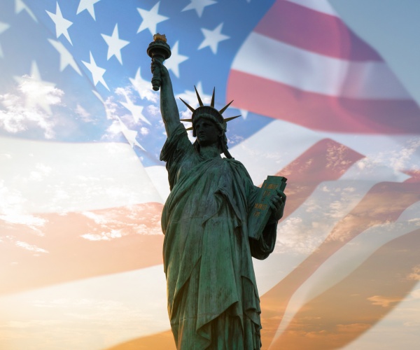 double exposure with statue of liberty and us flag blowing in the wind