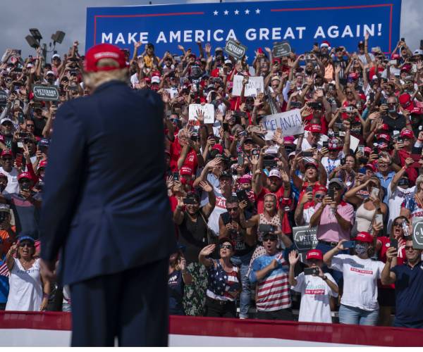 donald trump seen from the back at a rally and pointing to a cheering crowd of supporters