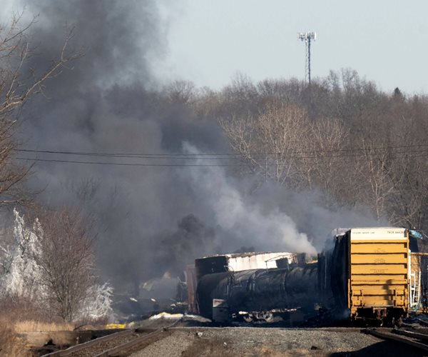 smoke rises from a derailed cargo train