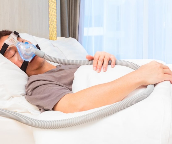 man sleeping in bed with CPAP mask