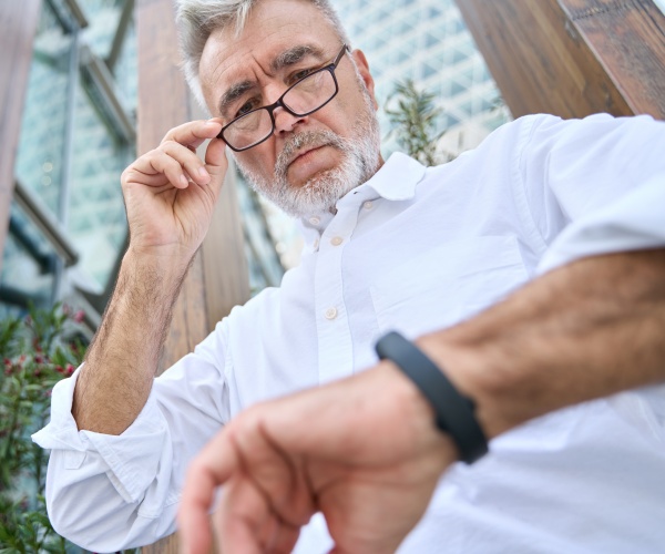 older man looking down at smartwatch on his wrist