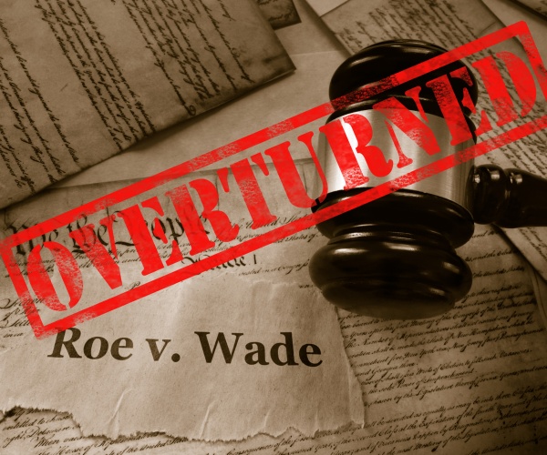 roe v wade news headline with gavel and overturned stamp on a copy of us constitution