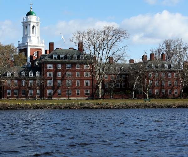 a body of water in the foreground and college campus buildings in the background