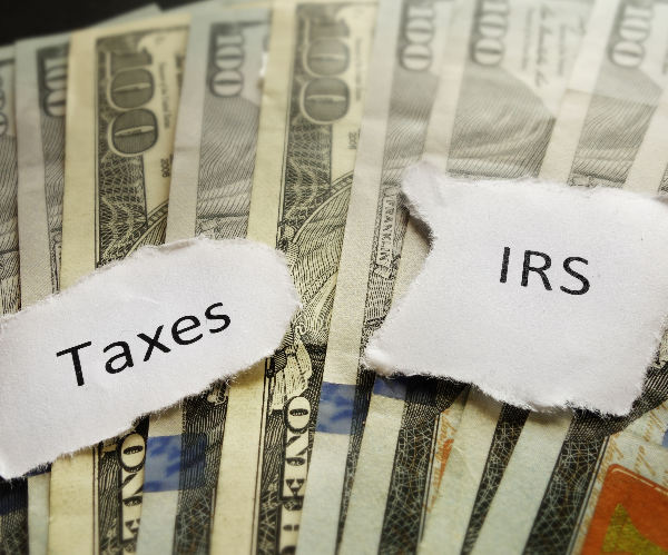 the words taxes and irs on pieces of paper on a stack of money