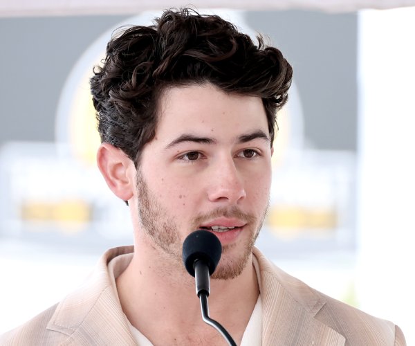 Nick Jonas speaks into a microphone