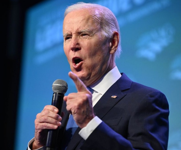 closeup of joe biden with mic pointing and wearing american flag pin