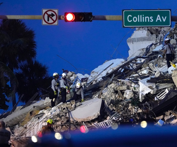 rescue workers look through the rubble where a wing of a 12-story beachfront condo building collapsed