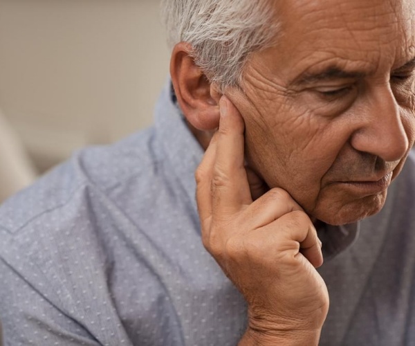 older man with hand to ear trying to hear 