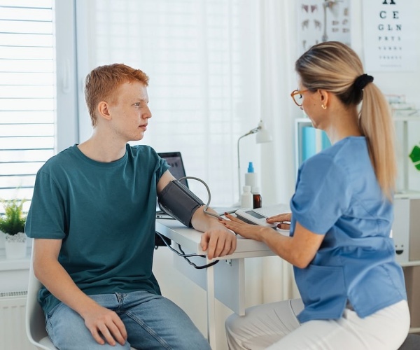 teenage boy getting his blood pressure checked in doctor's office