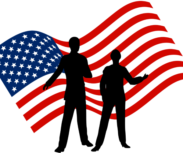 two candidates seen standing in front of a large american flag