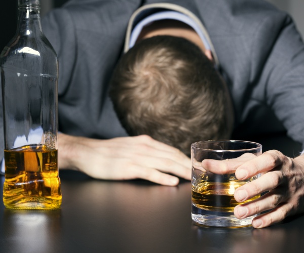 businessman face down on bar, glass and bottle of liquor