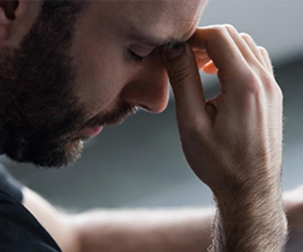 man with headache holding area above nose in pain