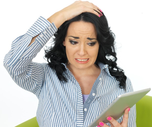 a woman holding a tablet device and looking frustrated