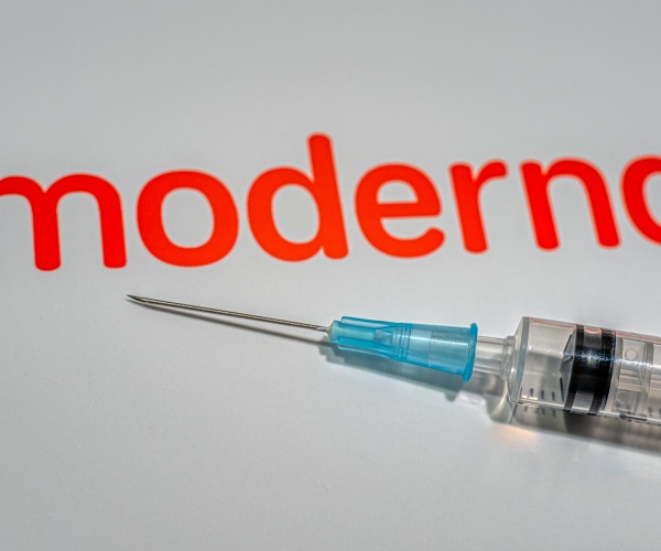 syringe with Moderna logo in background