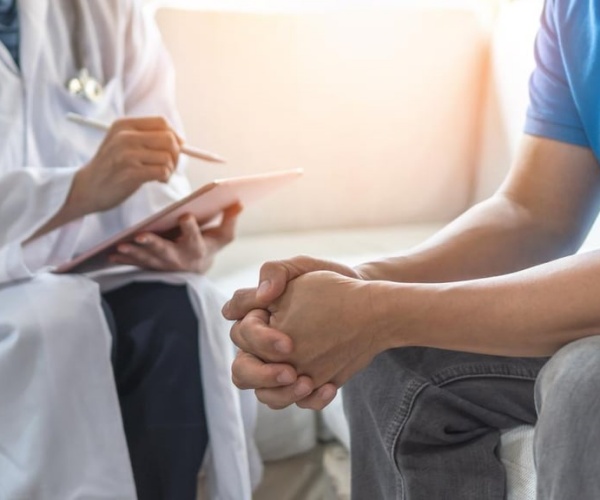 a teenaged boy talking to a psychiatrist with a clipboard