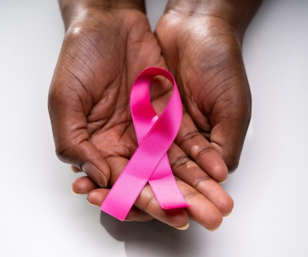 woman's hands holding pink ribbon for breast cancer awareness