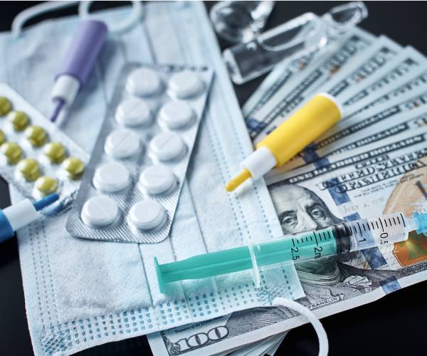 pills, syringes and a medical mask on top of hundred dollar bills.