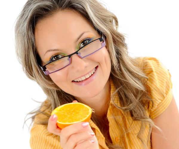 woman smiling, holding an orange