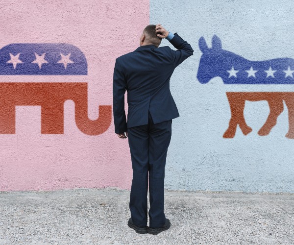 man thinks in the background wall with symbols of republican  and democratic parties