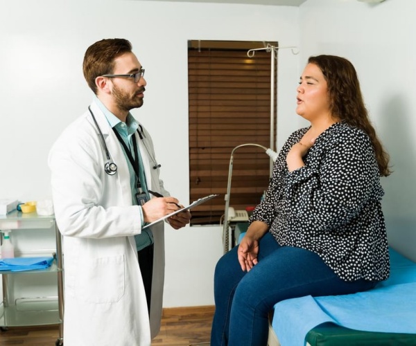 an overweight woman on examining table talking to her doctor