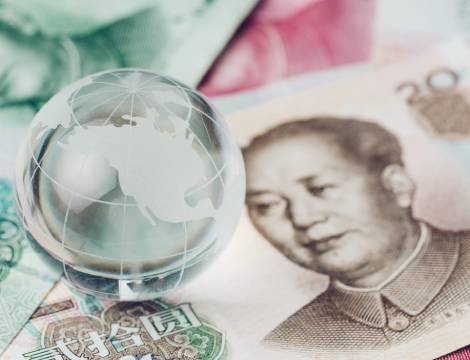 a small globe sitting on chinese currency notes