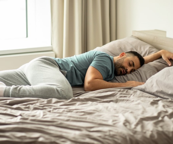 man sleeping in messy bed