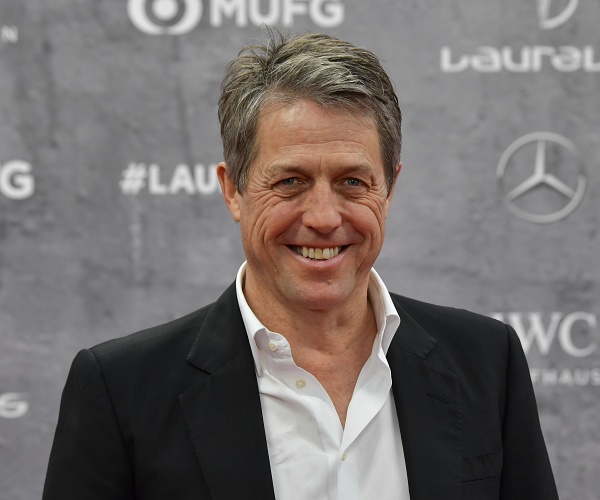 hugh grant stands on red carpet