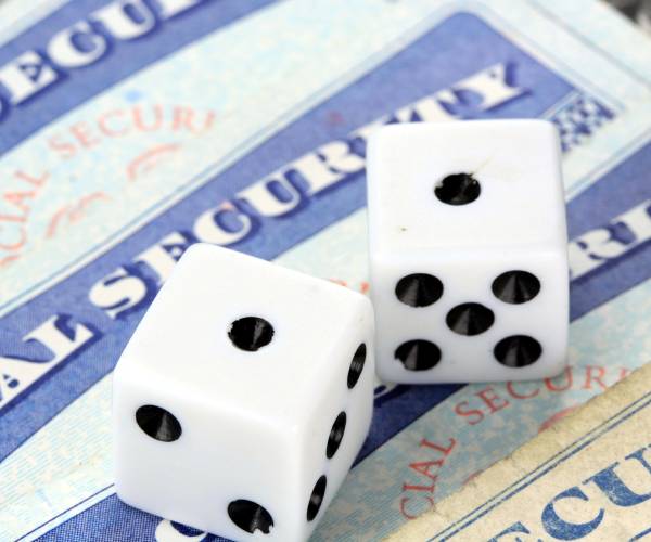 social security cards on a table with a pair of dice on top that have rolled two ones or snake eyes