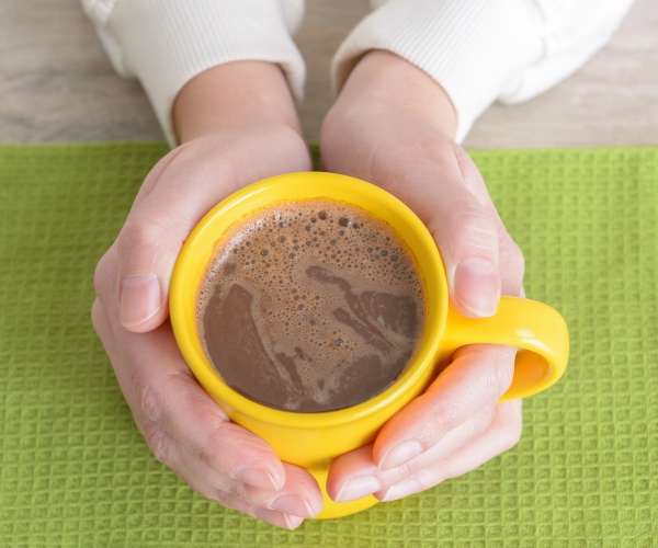 person's hands around a mug of hot cocoa