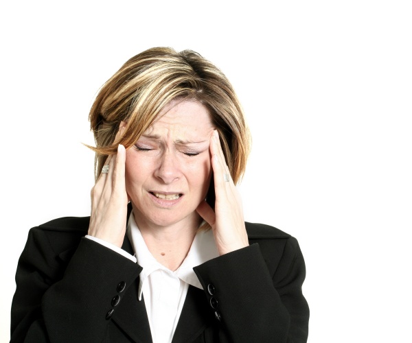 Business woman with hands to head suffering severe migraine