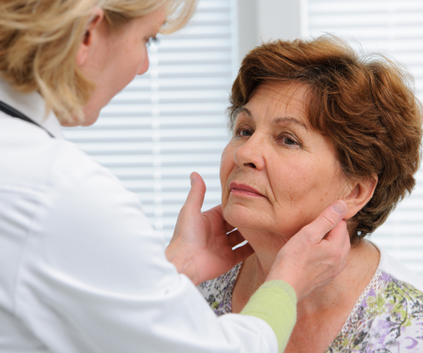 a doctor checks a patient's thyroid