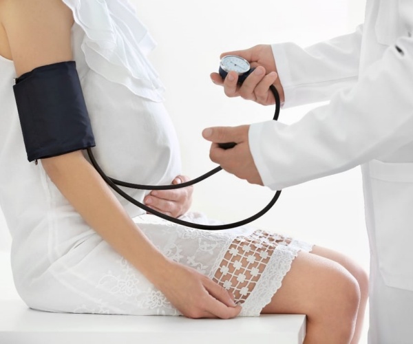 doctor taking blood pressure of pregnant woman