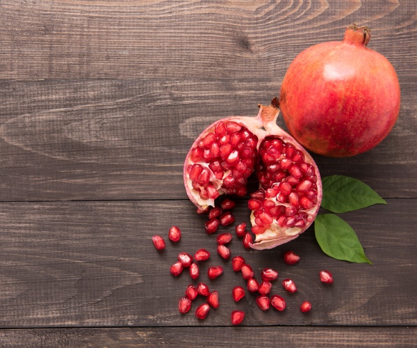 an unopened and opened pomegranate on wood table